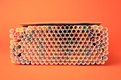 Photo of Box with many paper drinking straws on orange background