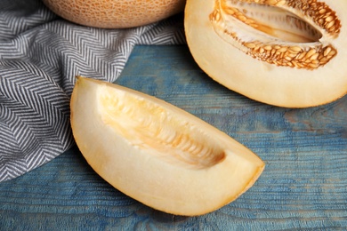 Photo of Tasty cut ripe melon on blue wooden table