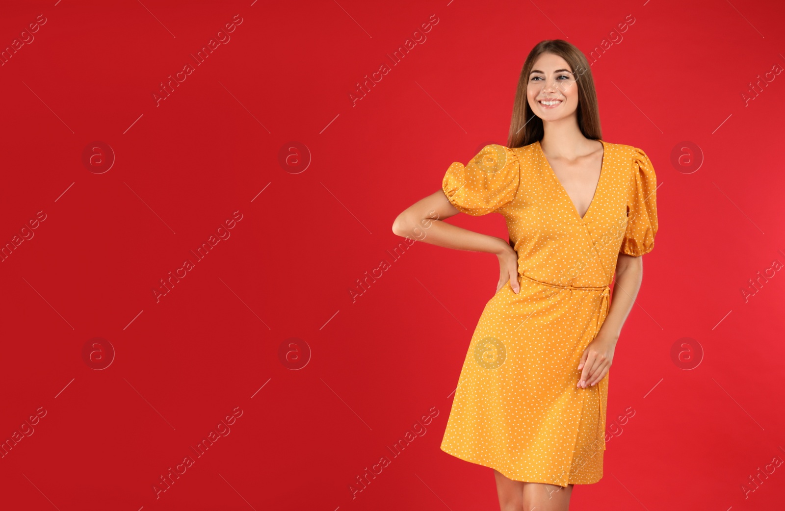 Photo of Young woman wearing stylish yellow dress on red background