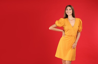 Photo of Young woman wearing stylish yellow dress on red background