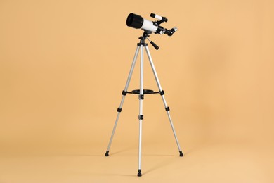 Photo of Tripod with modern telescope on beige background