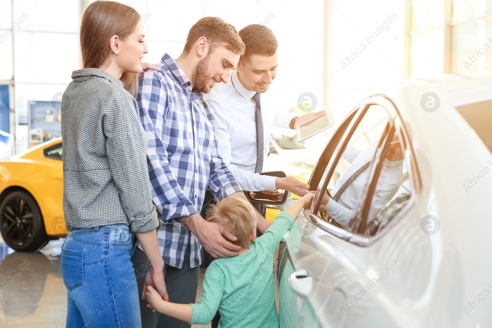 Photo of Young family choosing new car with salesman in salon