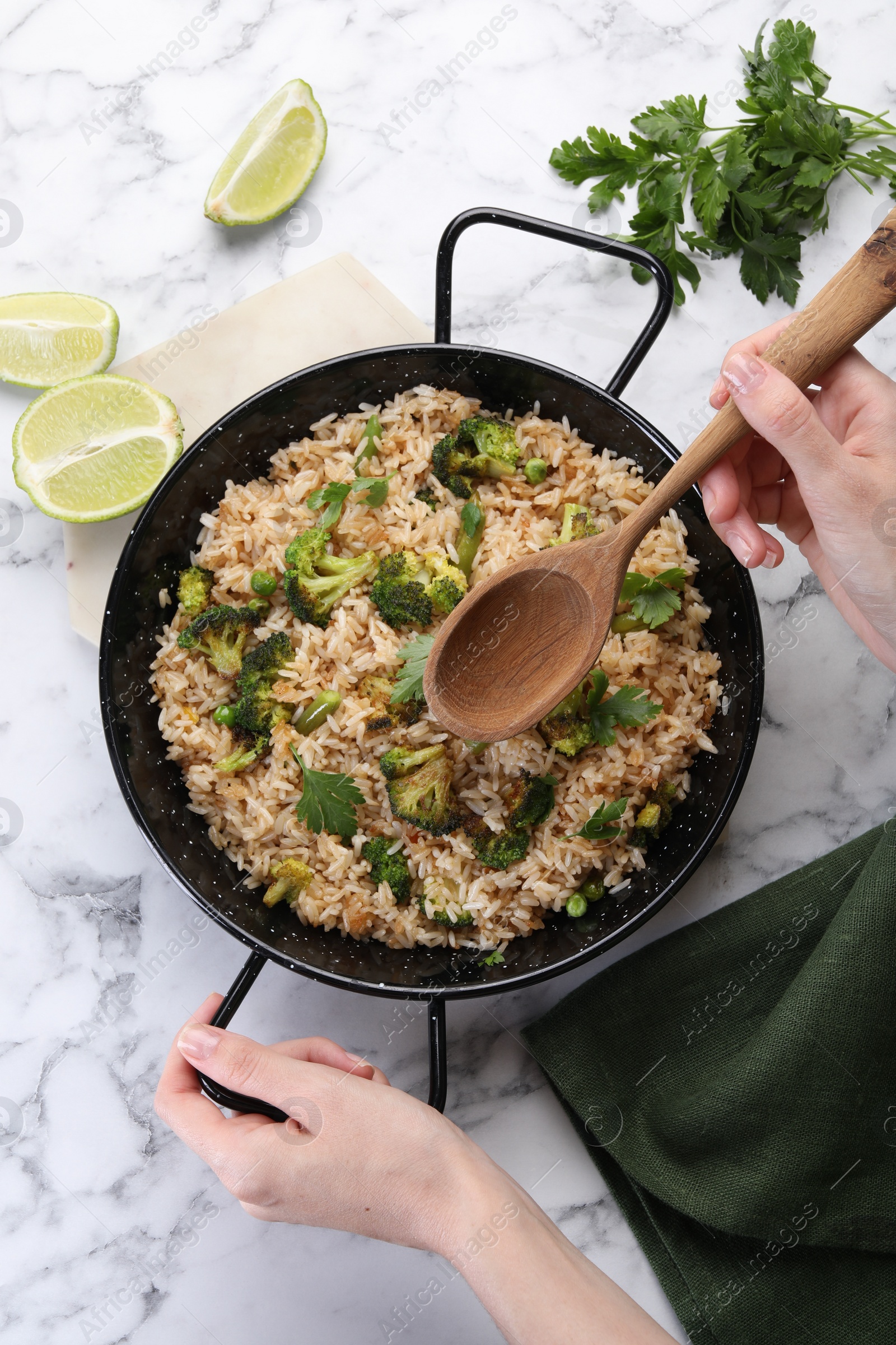 Photo of Woman with tasty fried rice and wooden spoon at white marble table, top view