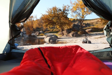 Camping tent with sleeping bag in wilderness, view from inside