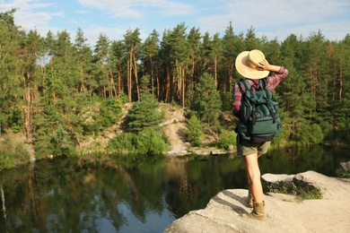 Photo of Young woman on rock near lake and forest. Camping season