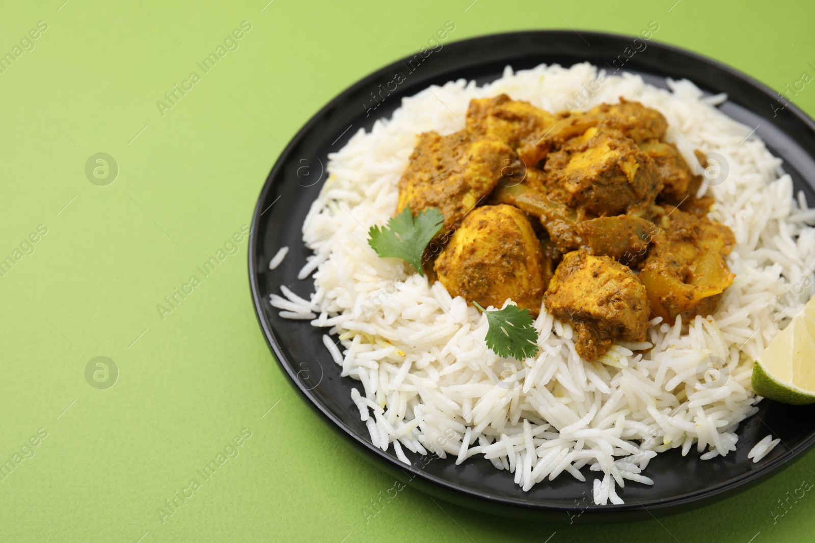 Photo of Delicious chicken curry with rice on green background, closeup