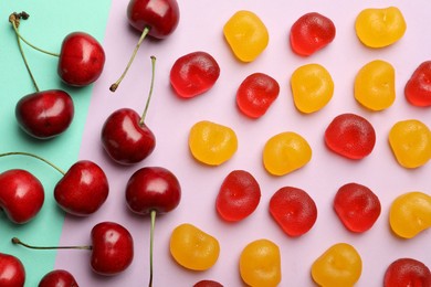 Photo of Delicious gummy cherry candies and fresh fruits on color background, flat lay