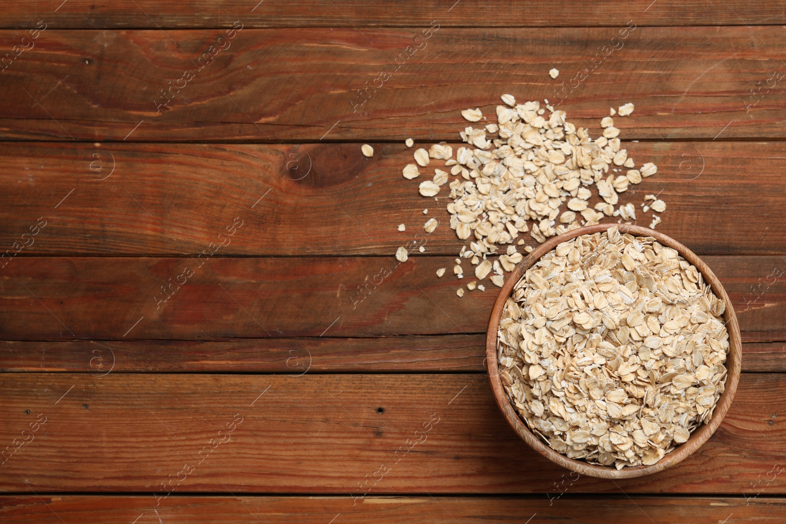 Photo of Bowl with oatmeal on wooden table, flat lay. Space for text