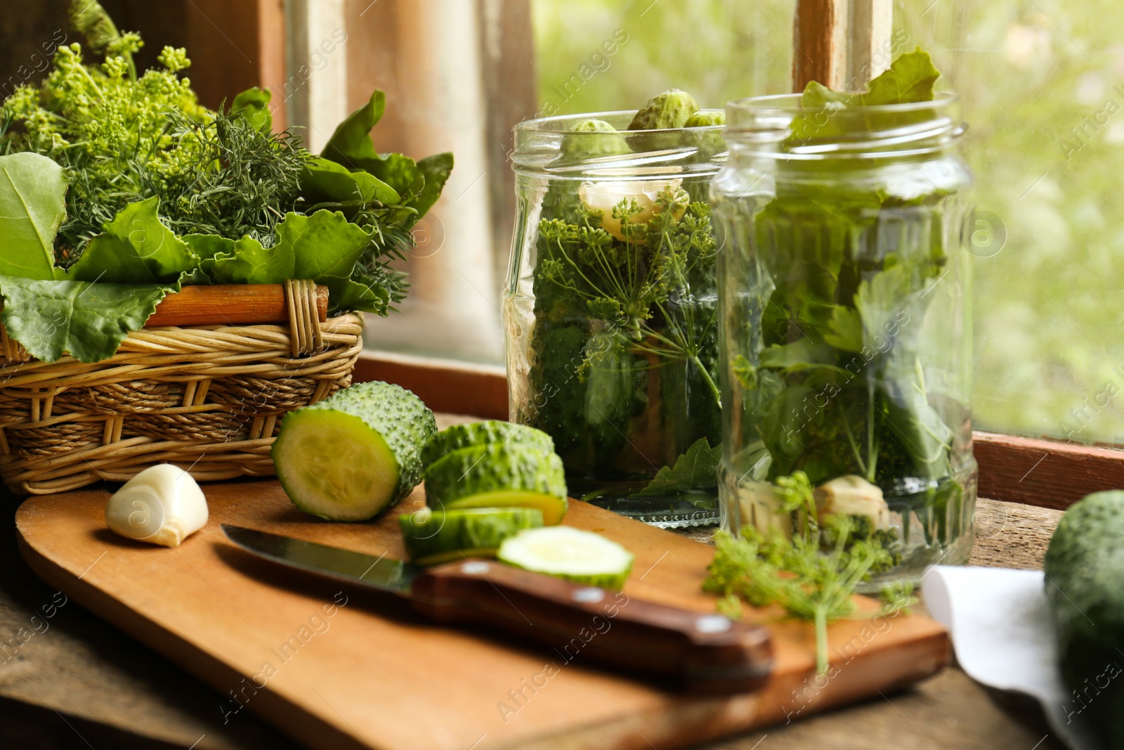 Photo of Glass jars, fresh vegetables and herbs on wooden table indoors. Pickling recipe