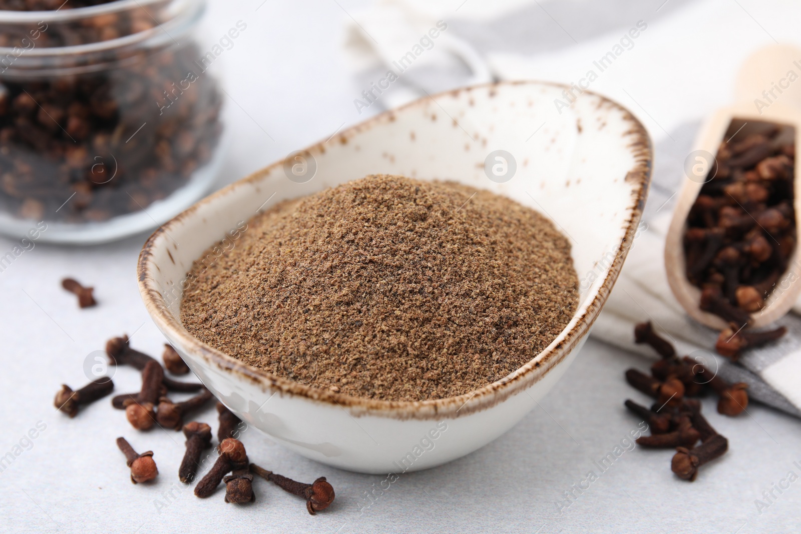 Photo of Aromatic clove powder and dried buds on light table, closeup