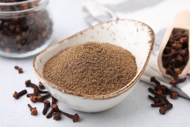 Photo of Aromatic clove powder and dried buds on light table, closeup