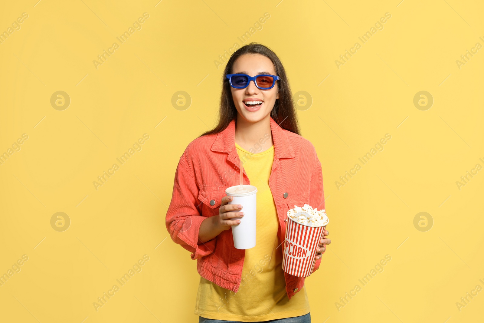 Photo of Woman with 3D glasses, popcorn and beverage during cinema show on color background