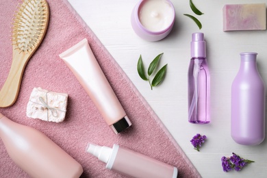 Photo of Flat lay composition with hair cosmetic products and towel on white wooden table