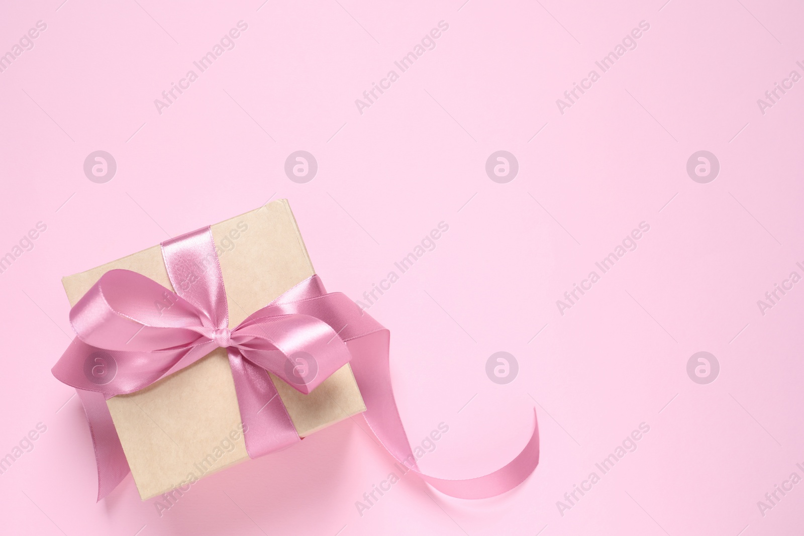 Photo of Beautiful gift box with bow on pink background, top view. Space for text