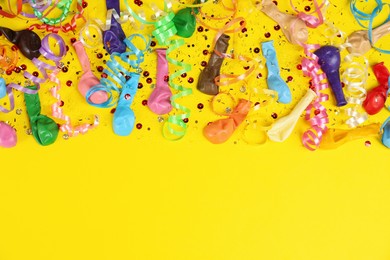 Photo of Colorful serpentine streamers, confetti and balloons on yellow background, flat lay. Space for text