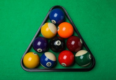Photo of Plastic rack with billiard balls on green table, top view