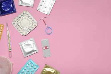 Contraceptive pills, condoms, intrauterine device and thermometer on pink background, flat lay and space for text. Different birth control methods