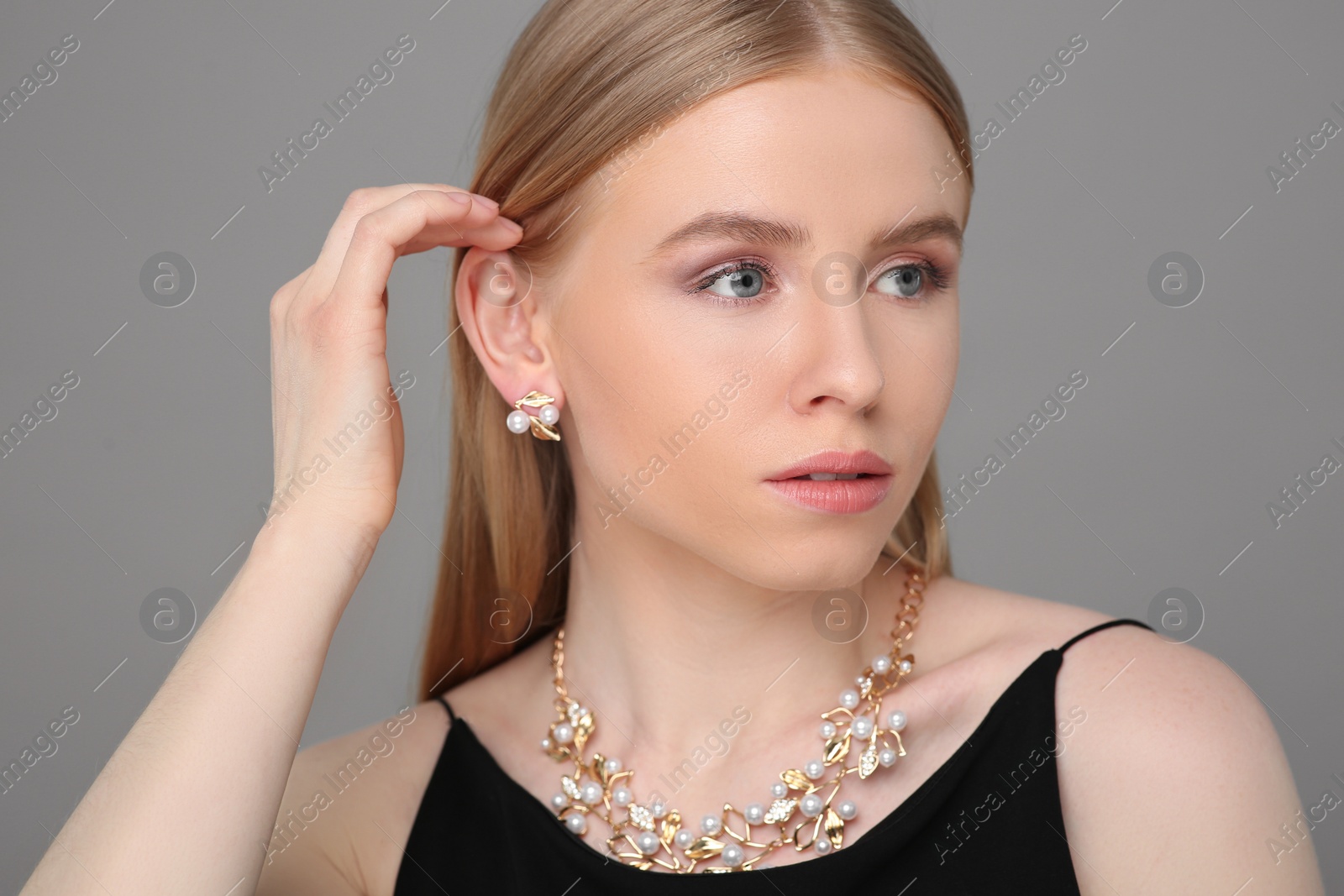 Photo of Beautiful young woman with elegant jewelry on gray background