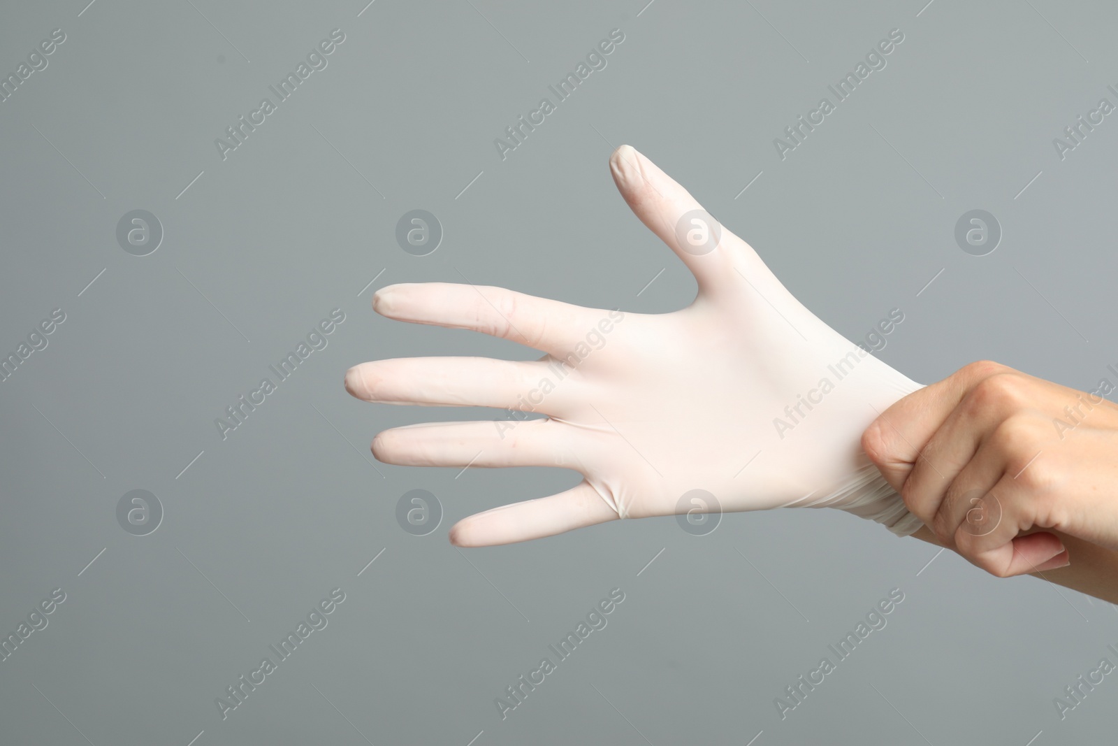 Photo of Doctor wearing medical gloves on grey background, closeup