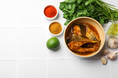 Photo of Tasty fish curry and ingredients on white tiled table, flat lay. Space for text. Indian cuisine