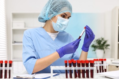 Laboratory testing. Doctor with blood samples in tubes at white table indoors