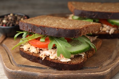 Delicious sandwiches with tuna and vegetables on wooden serving board, closeup