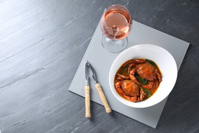 Delicious boiled crabs with sauce, glass of wine and cracker on grey table, top view. Space for text