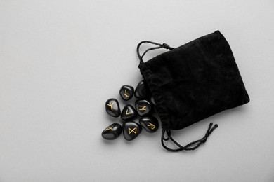Photo of Bag with black rune stones on light grey background, flat lay. Space for text