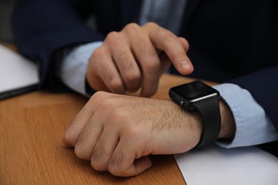 Businessman with smart watch at desk in office, closeup