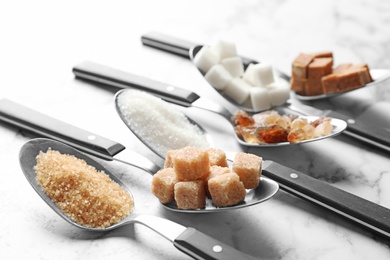 Spoons with different types of sugar on table