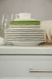 Clean plates, cup and glasses on white countertop in kitchen