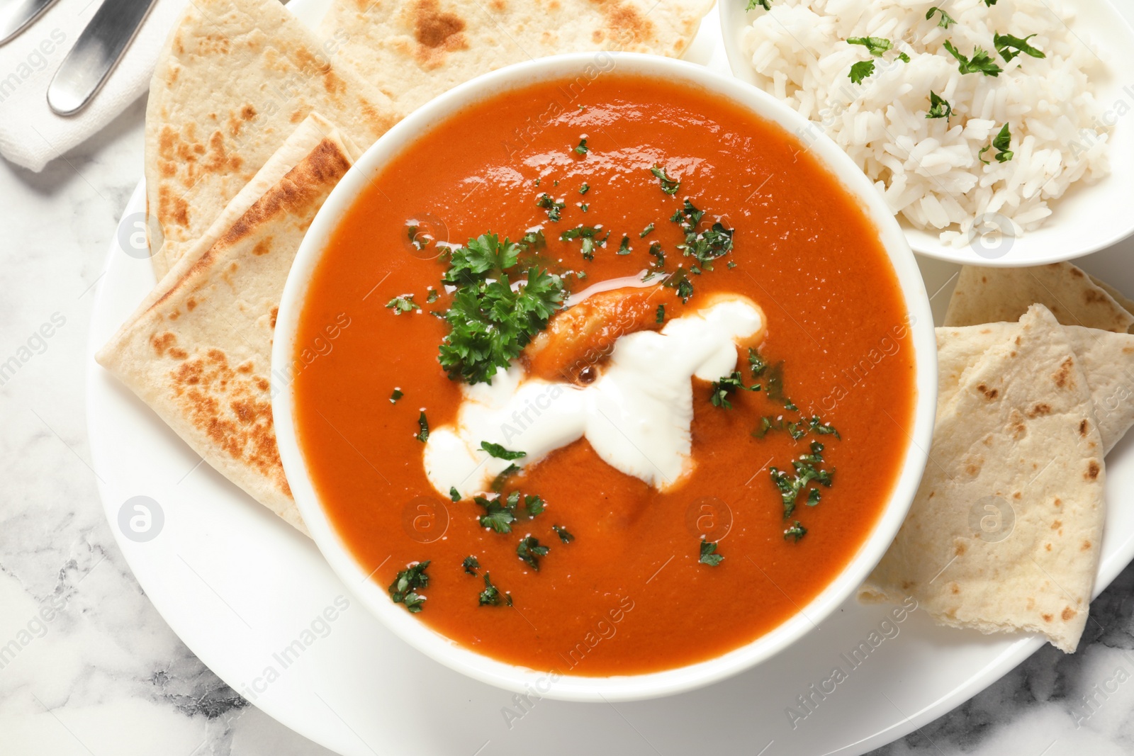 Photo of Delicious butter chicken served on marble table, top view. Traditional Murgh Makhani dish