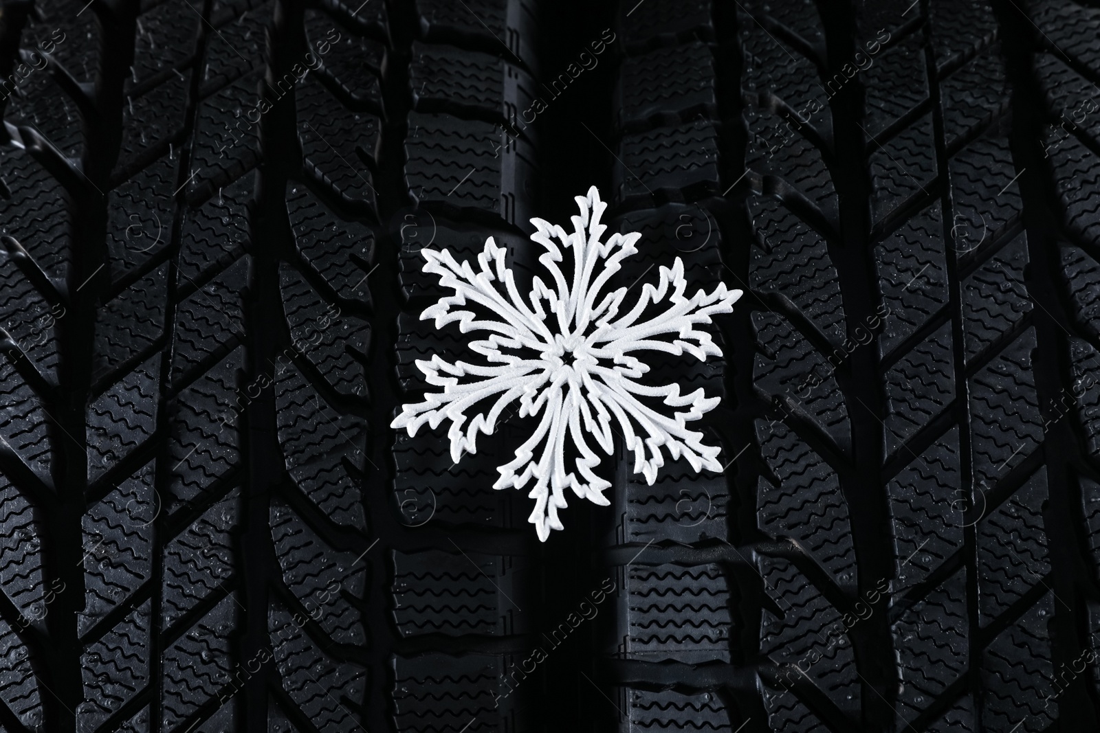 Photo of Winter tires with decorative snowflake as background, closeup