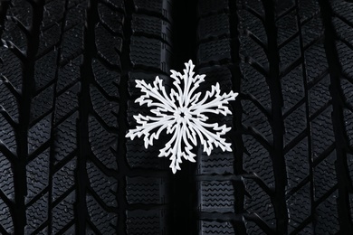 Photo of Winter tires with decorative snowflake as background, closeup