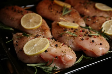 Photo of Chicken breasts with lemon and rosemary on baking sheet, closeup