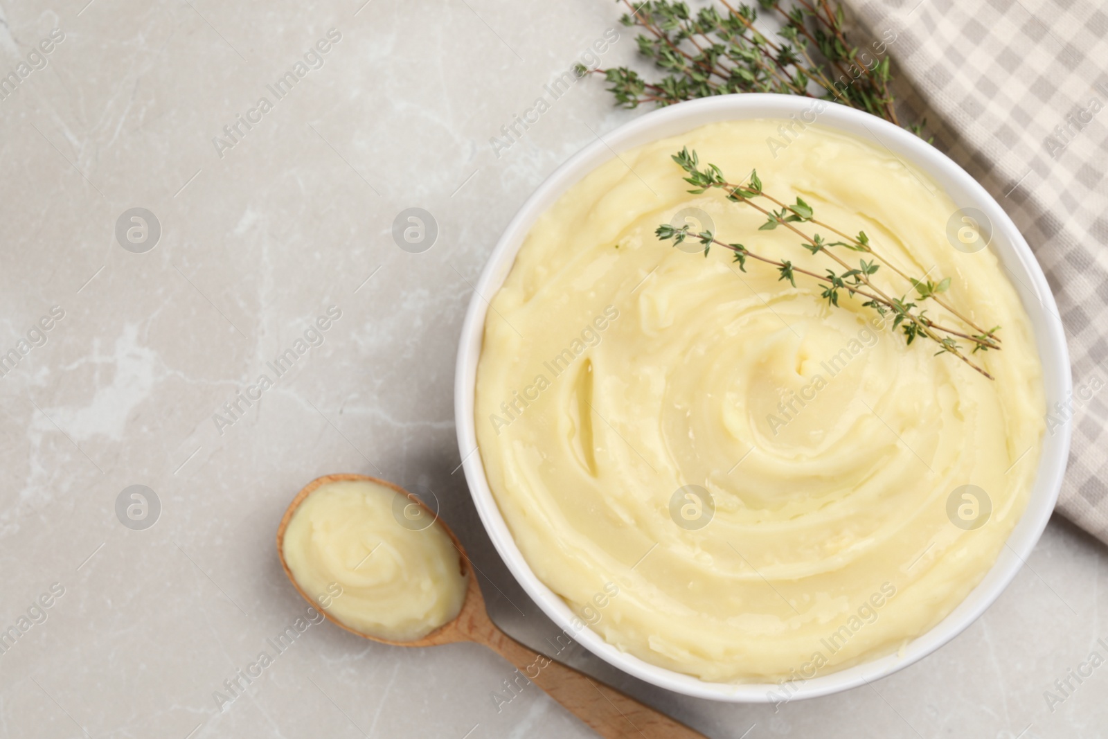Photo of Bowl of tasty mashed potato with rosemary on grey marble table, flat lay. Space for text