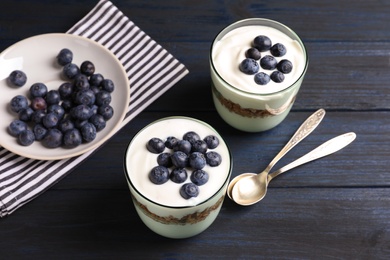 Photo of Glasses with yogurt, berries and granola on table