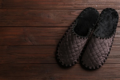 Photo of Pair of soft slippers on wooden background, flat lay. Space for text