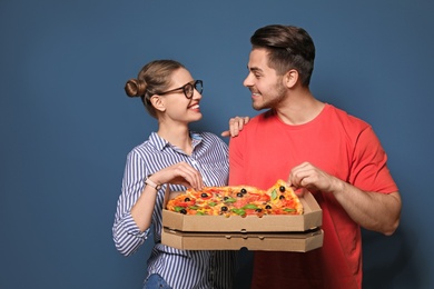 Photo of Attractive young couple with delicious pizza on color background