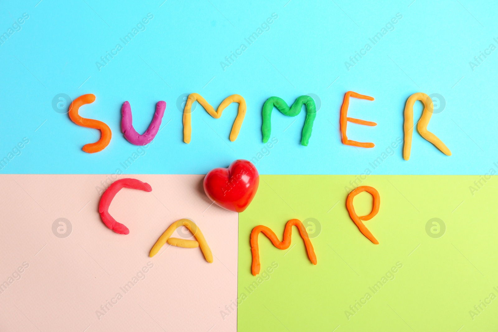 Photo of Words SUMMER CAMP made from modelling clay and small red heart on color background, top view