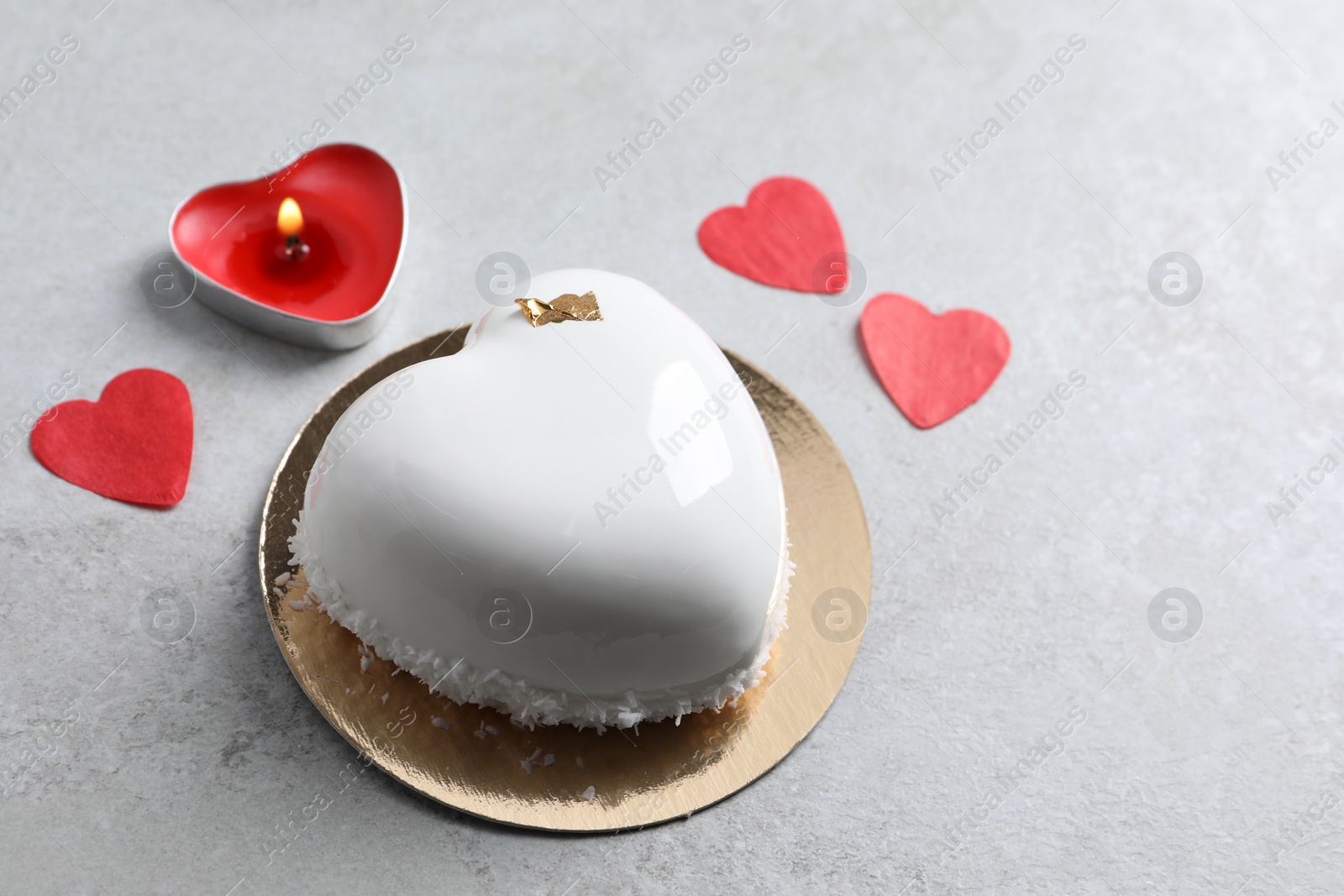 Photo of St. Valentine's Day. Delicious heart shaped cake, candle and confetti on light table, space for text