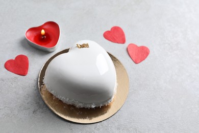 St. Valentine's Day. Delicious heart shaped cake, candle and confetti on light table, space for text