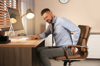 Photo of Man suffering from hemorrhoid at workplace in office