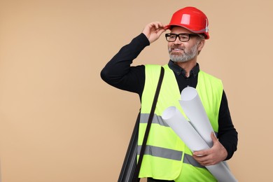 Architect in hard hat holding drafts on beige background. Space for text