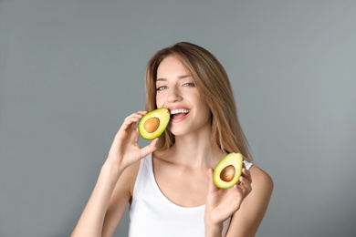 Portrait of young beautiful woman with ripe delicious avocado on color background