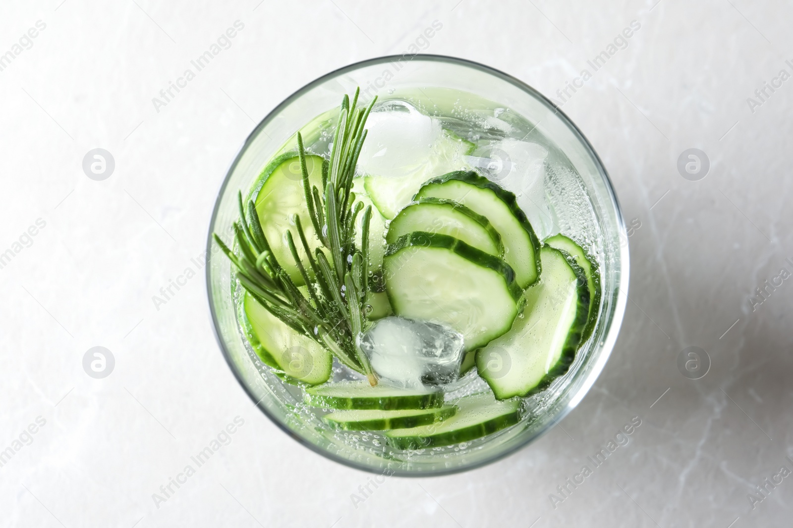 Photo of Glass of fresh cucumber water on light background, top view