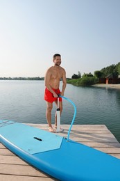 Man pumping up SUP board on pier