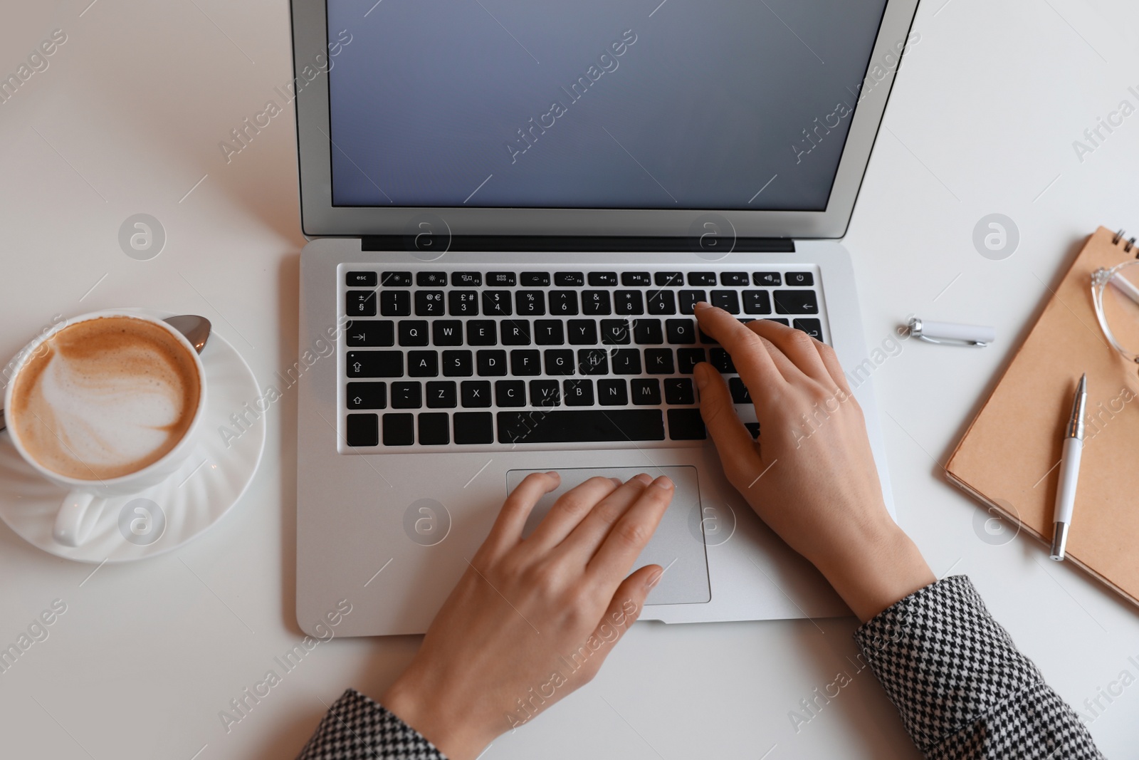 Photo of Young blogger working with laptop at table in cafe, above view