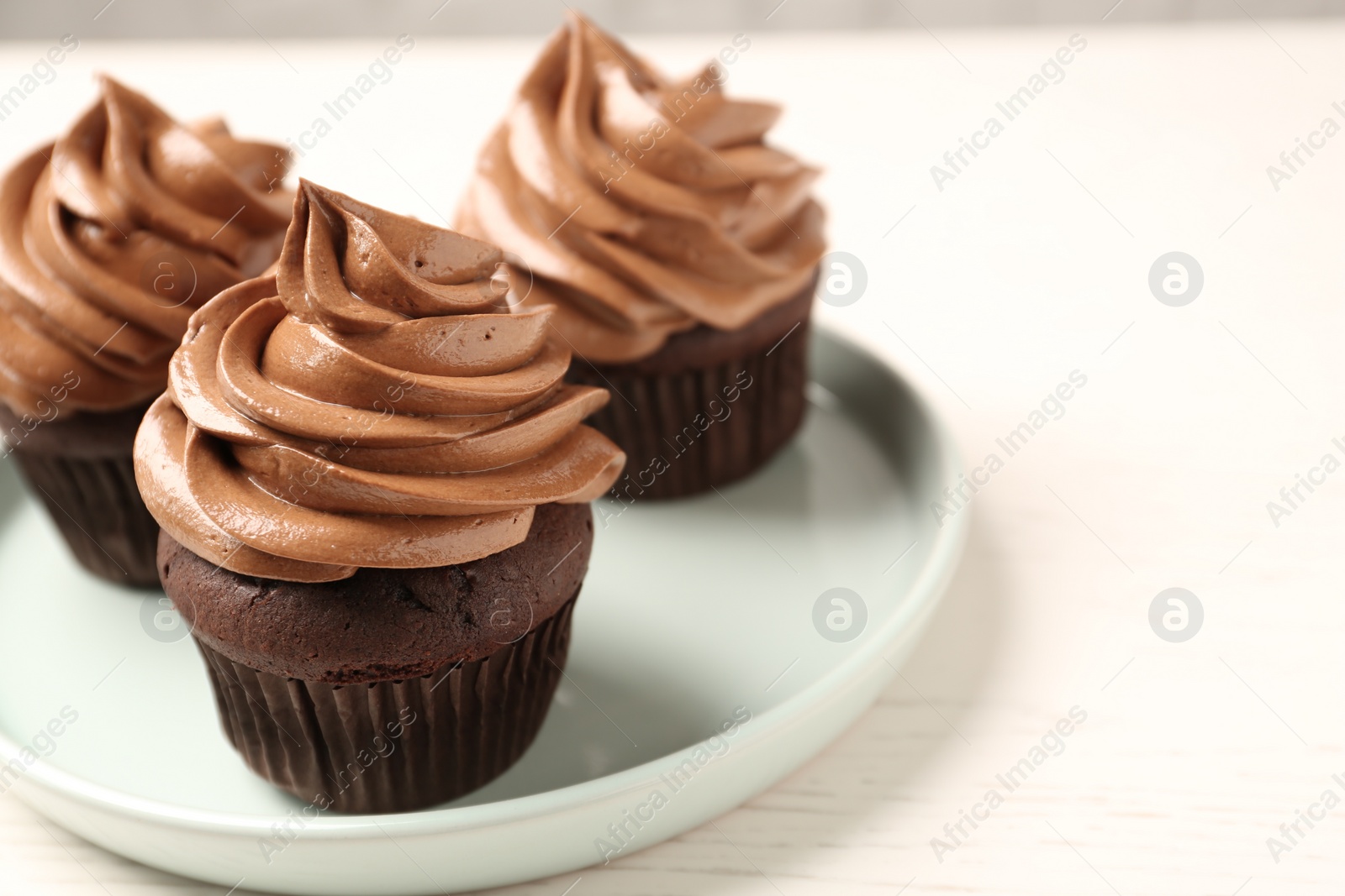 Photo of Delicious fresh chocolate cupcakes with cream on white table, closeup