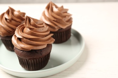 Delicious fresh chocolate cupcakes with cream on white table, closeup